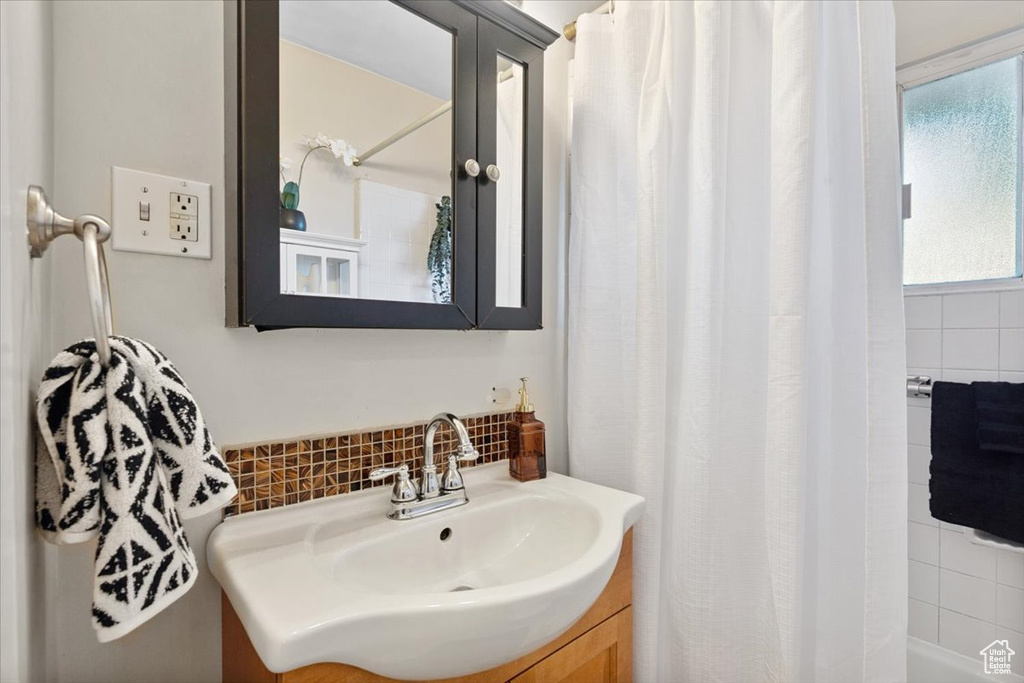 Full bath featuring vanity, backsplash, and shower / bath combination with curtain