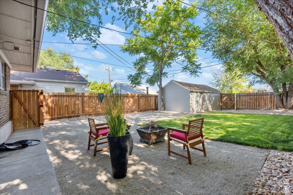 Fenced backyard with a patio area, an outdoor fire pit, a gate, and a storage shed