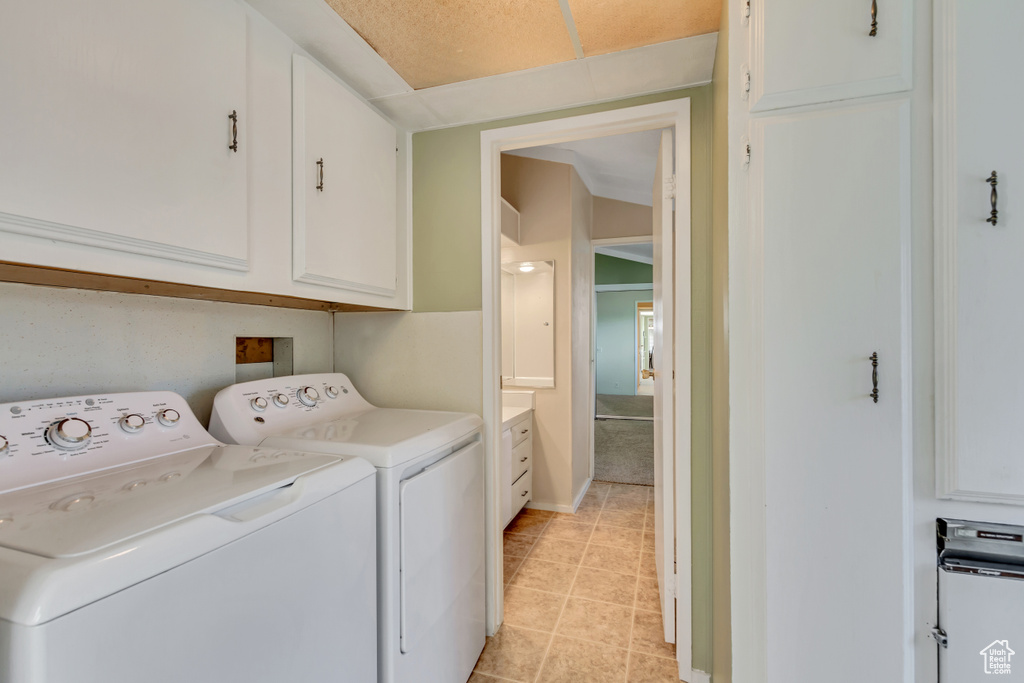 Laundry area with separate washer and dryer, cabinet space, and light tile patterned flooring