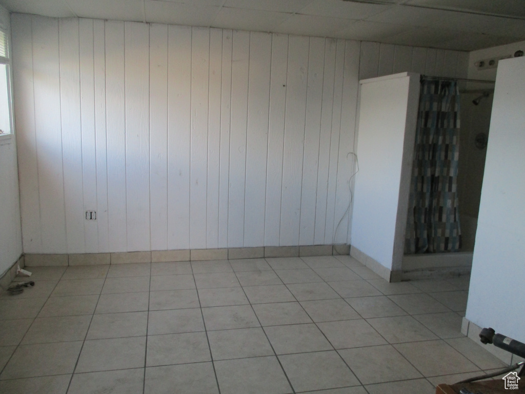 Unfurnished room featuring light tile patterned flooring and wooden walls