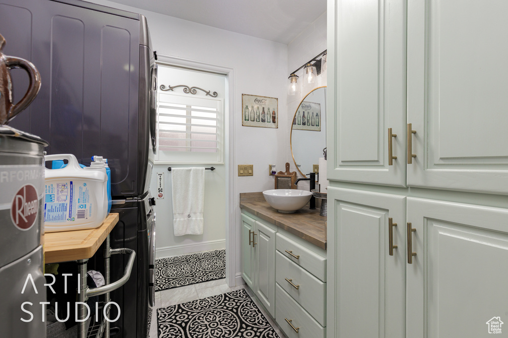 Bathroom with stacked washer and clothes dryer, vanity, and tile patterned floors