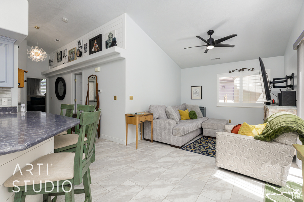 Living room with vaulted ceiling, a ceiling fan, and a chandelier