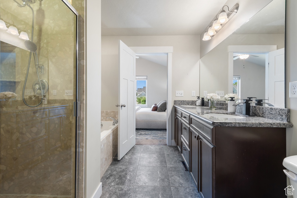 Ensuite bathroom featuring double vanity, a shower stall, a ceiling fan, a garden tub, and tile patterned floors