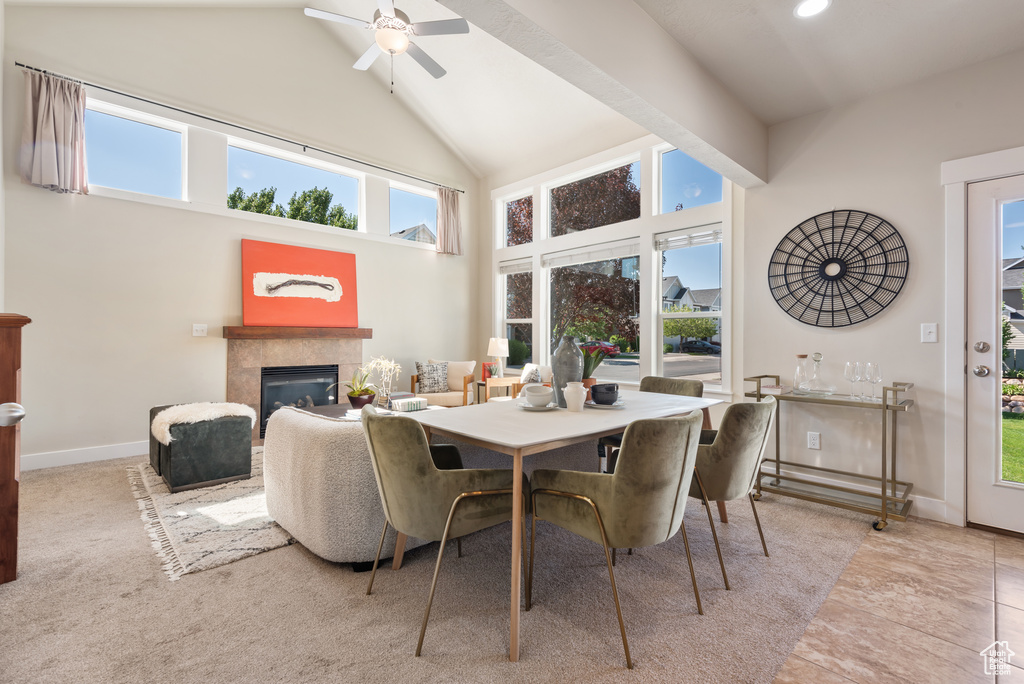 Dining area with a glass covered fireplace, a ceiling fan, and high vaulted ceiling