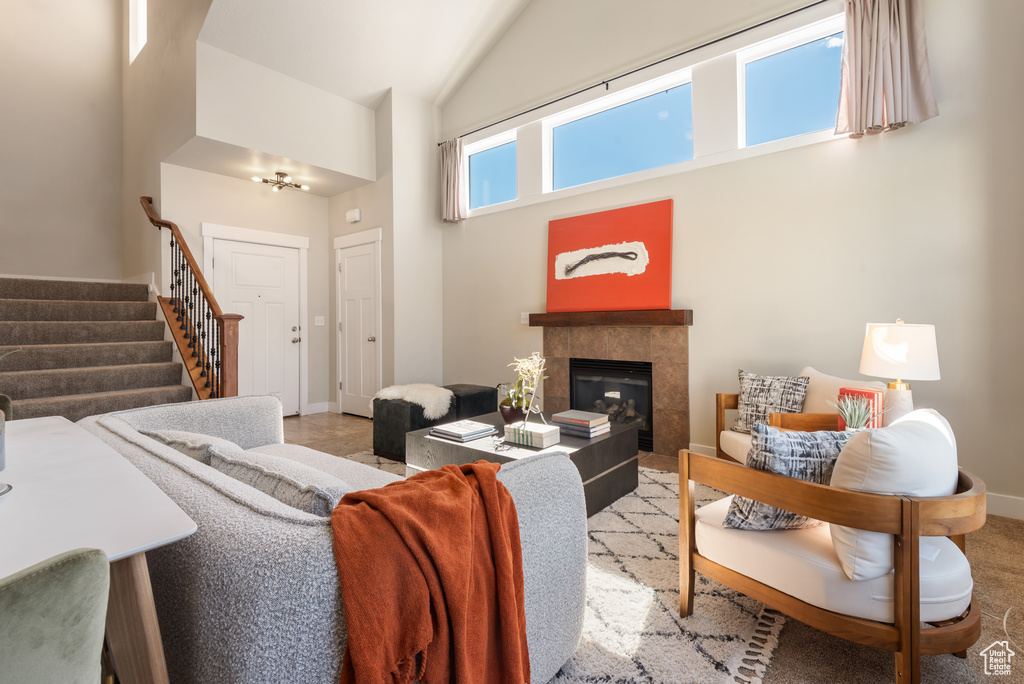 Living area with high vaulted ceiling, stairway, and a tile fireplace