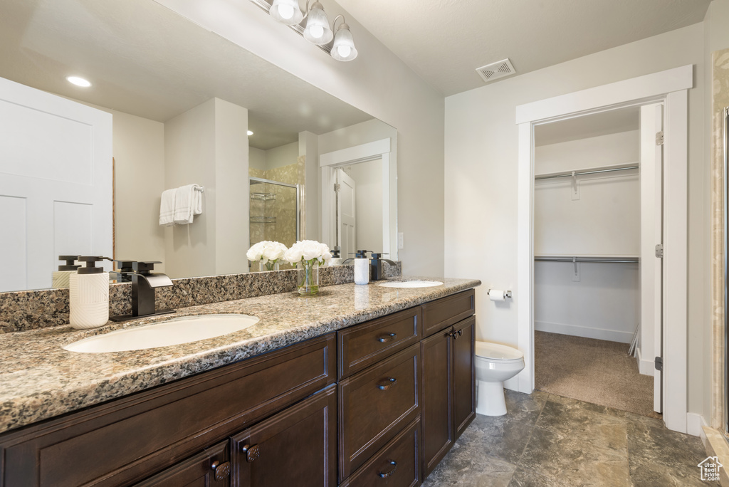 Bathroom with a shower stall, double vanity, stone finish floors, and a spacious closet