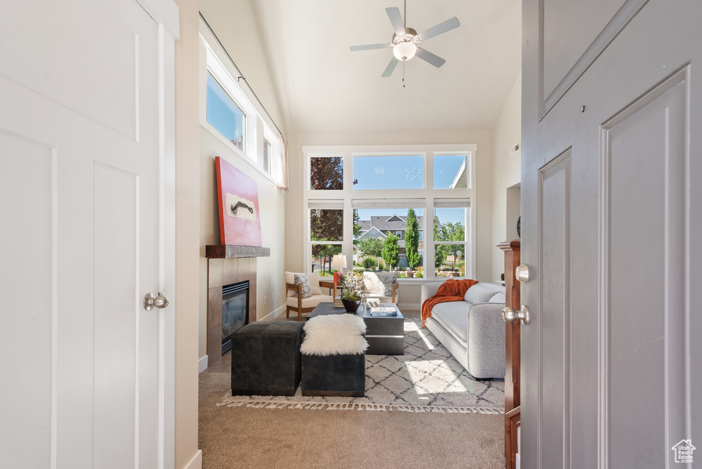 Carpeted living area featuring high vaulted ceiling, a fireplace, and a ceiling fan