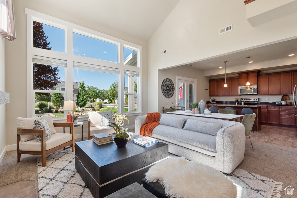 Living area with high vaulted ceiling and light colored carpet