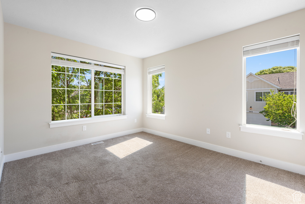 Carpeted spare room featuring baseboards