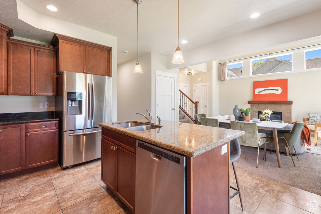 Kitchen with stainless steel appliances, a kitchen bar, light tile patterned floors, stone countertops, and recessed lighting