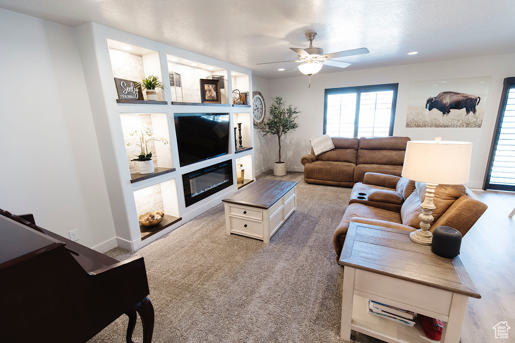 Living room with ceiling fan, a glass covered fireplace, and recessed lighting
