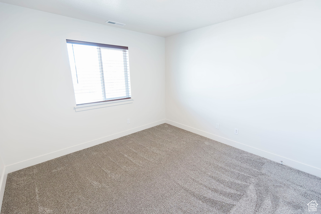 Carpeted spare room featuring baseboards