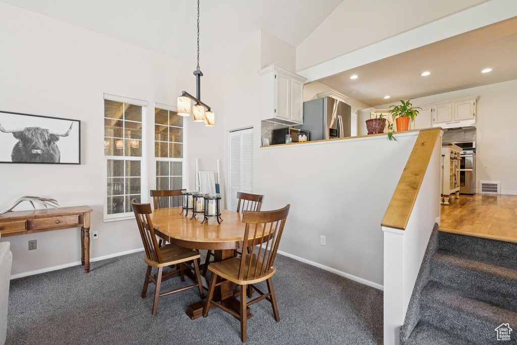 Dining space featuring dark colored carpet, recessed lighting, stairway, and vaulted ceiling