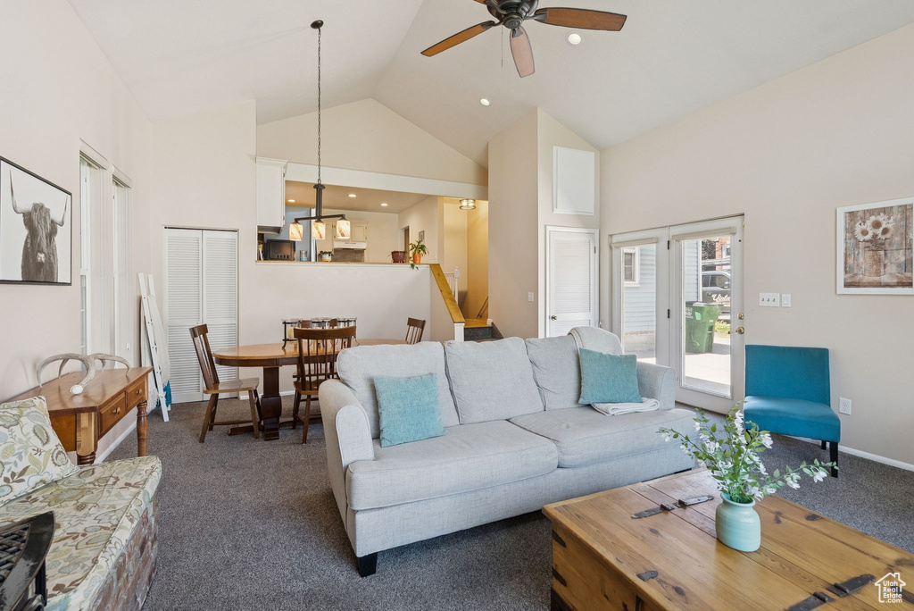 Living room with high vaulted ceiling, dark carpet, and a ceiling fan