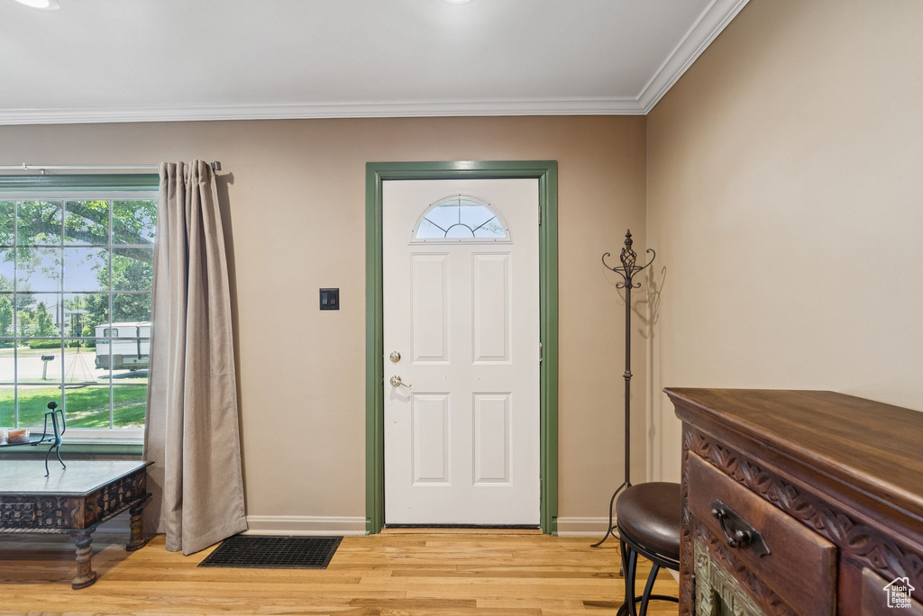 Foyer with light wood finished floors and ornamental molding