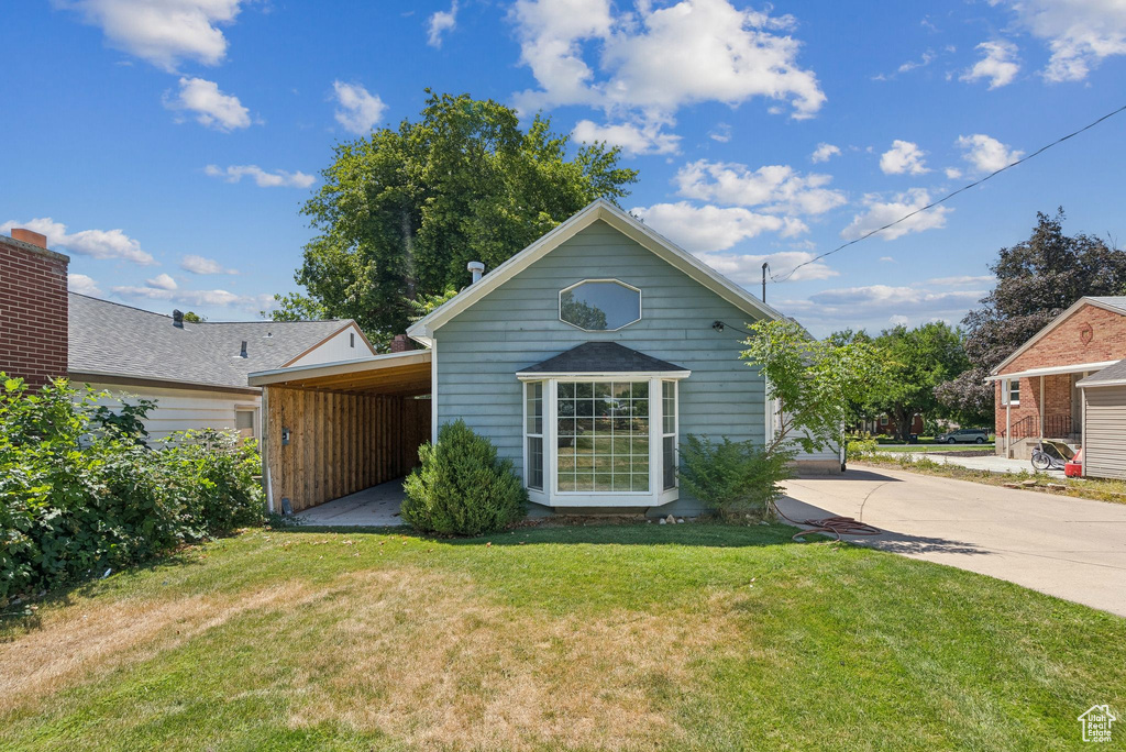 Rear view of property featuring a yard and concrete driveway