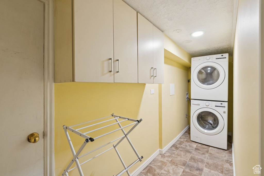 Washroom featuring stacked washer and clothes dryer and cabinet space