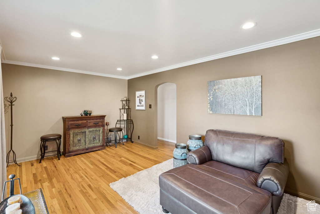 Living room with arched walkways, crown molding, recessed lighting, and light wood-style flooring