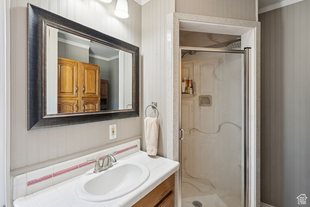 Full bath with ornamental molding, vanity, and a shower stall