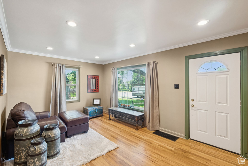 Foyer entrance with light wood finished floors, crown molding, and recessed lighting
