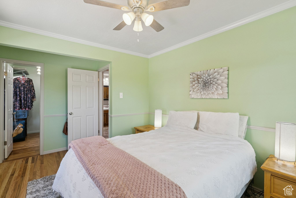 Bedroom featuring wood finished floors, ornamental molding, and ceiling fan