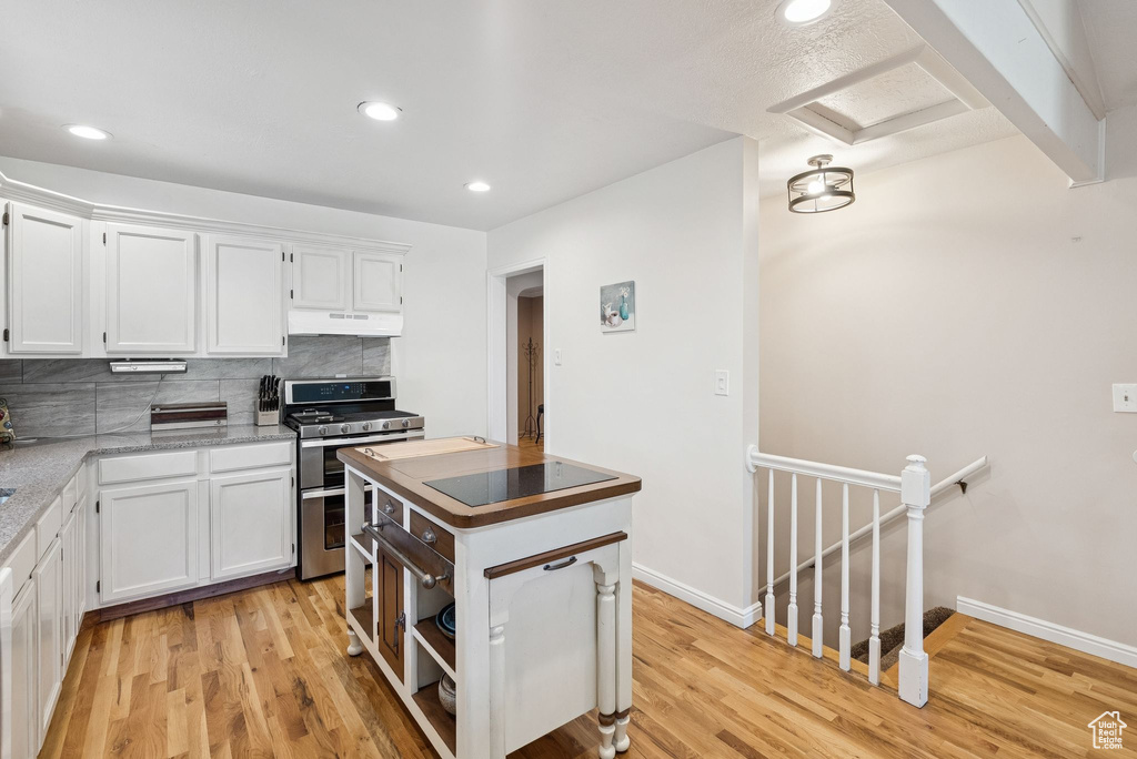 Kitchen featuring range with two ovens, under cabinet range hood, white cabinets, light wood-style floors, and recessed lighting