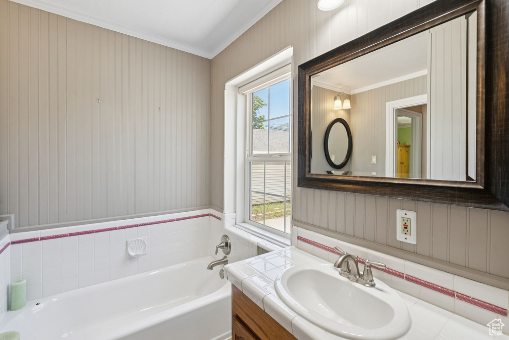 Bathroom featuring crown molding, plenty of natural light, a garden tub, wallpapered walls, and vanity