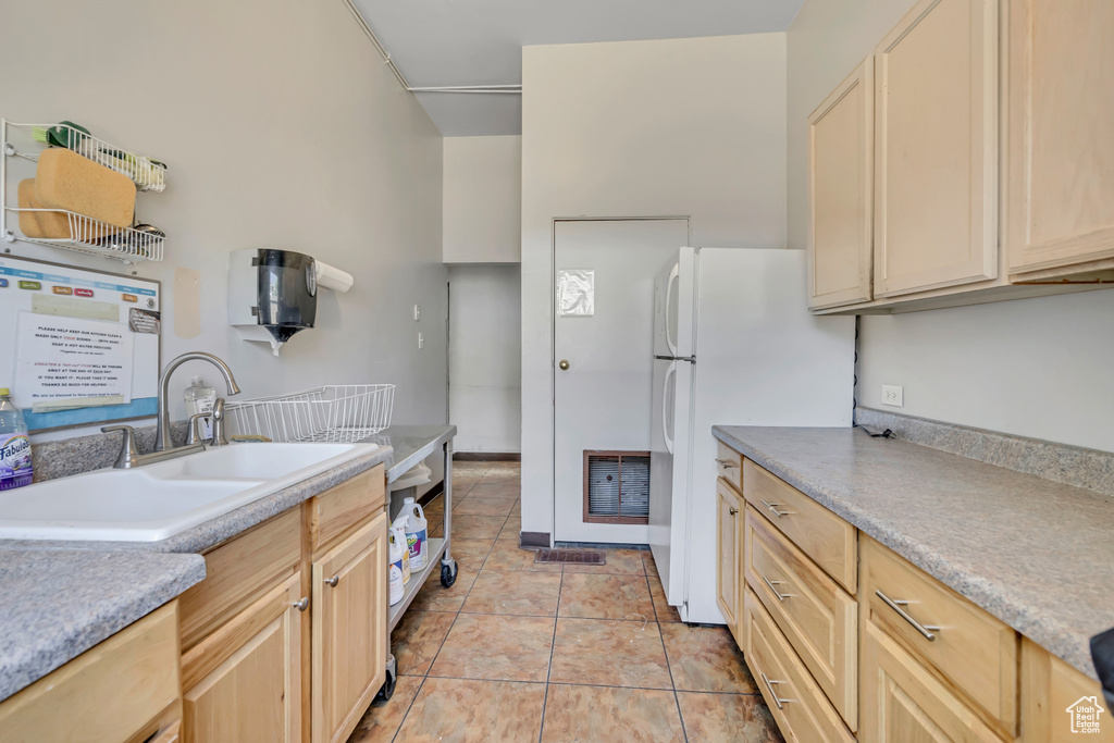 Kitchen with light brown cabinetry, freestanding refrigerator, and light countertops