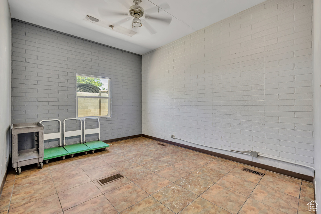 Unfurnished room featuring brick wall and a ceiling fan