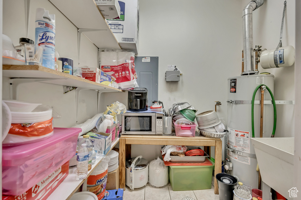 Storage area featuring strapped water heater and a sink