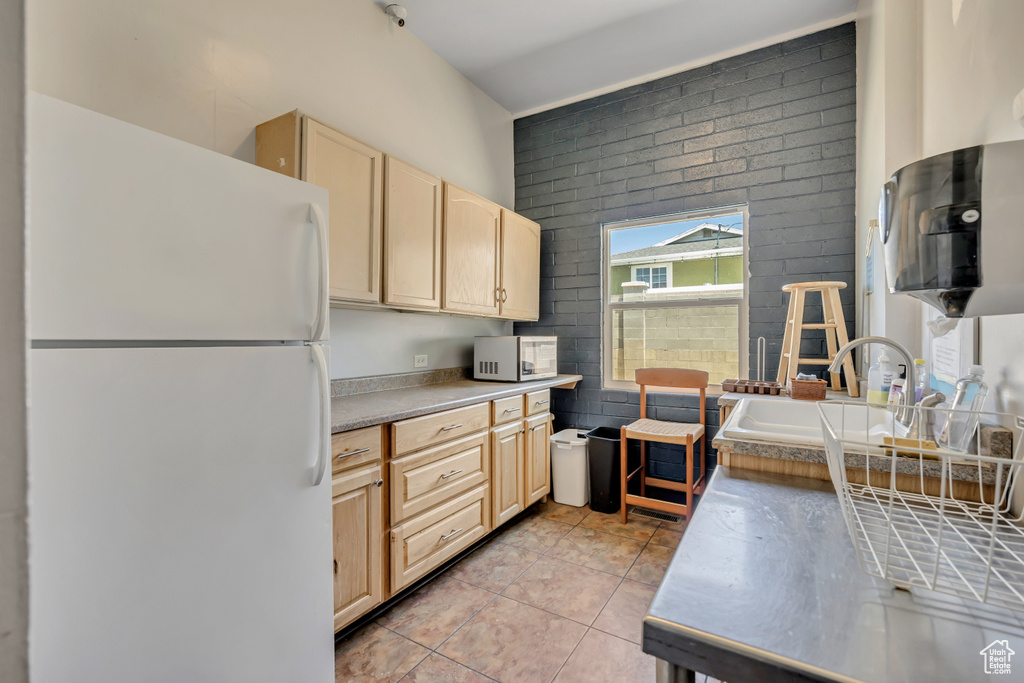 Kitchen featuring white appliances, light brown cabinets, light tile patterned flooring, and light countertops