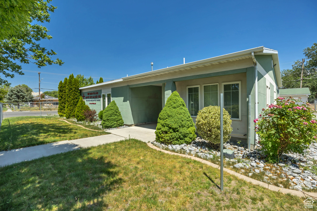 Ranch-style home featuring a front lawn, stucco siding, an attached garage, and concrete driveway