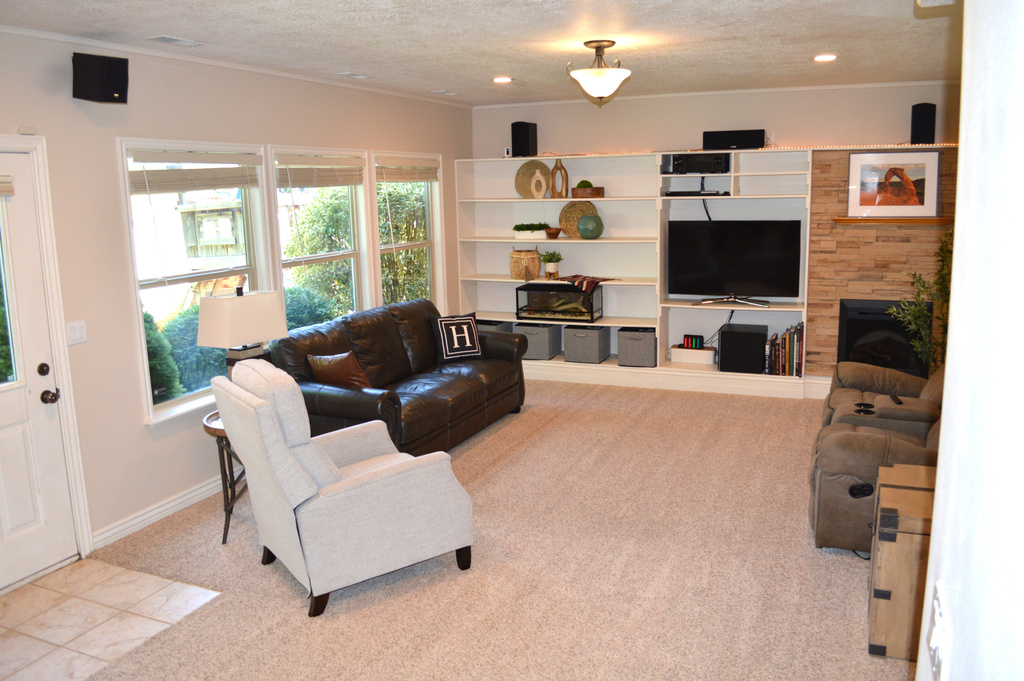 Living room featuring carpet, crown molding, recessed lighting, a textured ceiling, and a fireplace