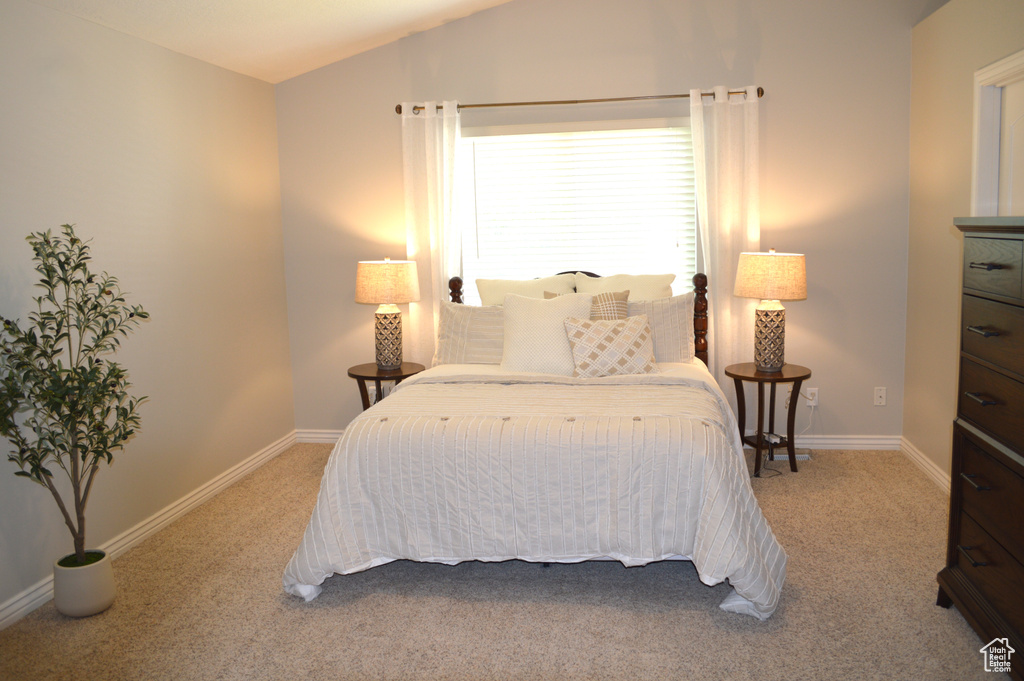 Carpeted bedroom featuring lofted ceiling and baseboards