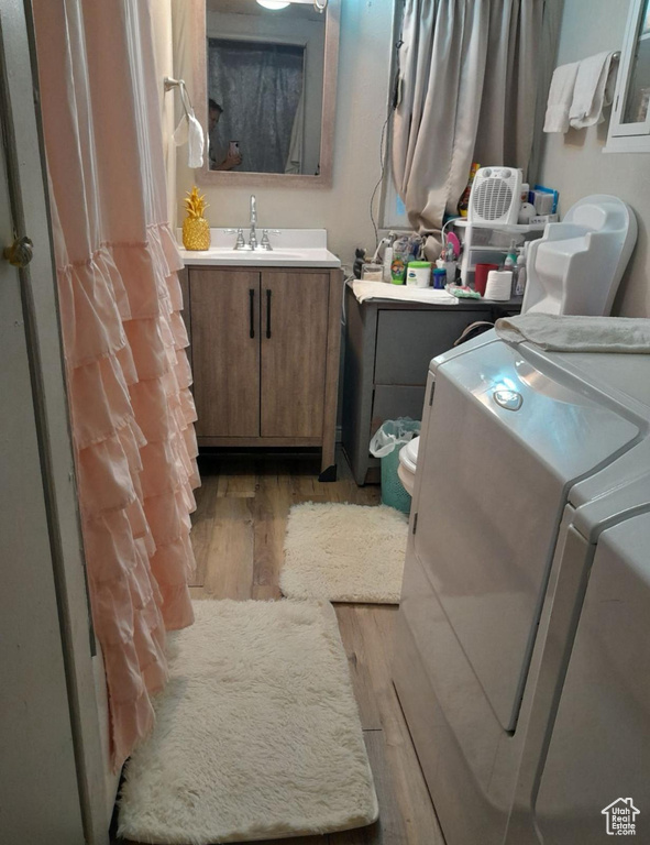 Bathroom featuring wood finished floors, washing machine and dryer, and vanity