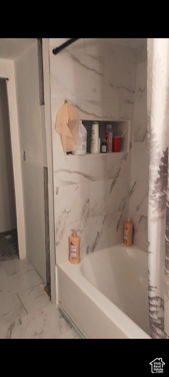 Bathroom with shower / bath combination with curtain and marble finish floors