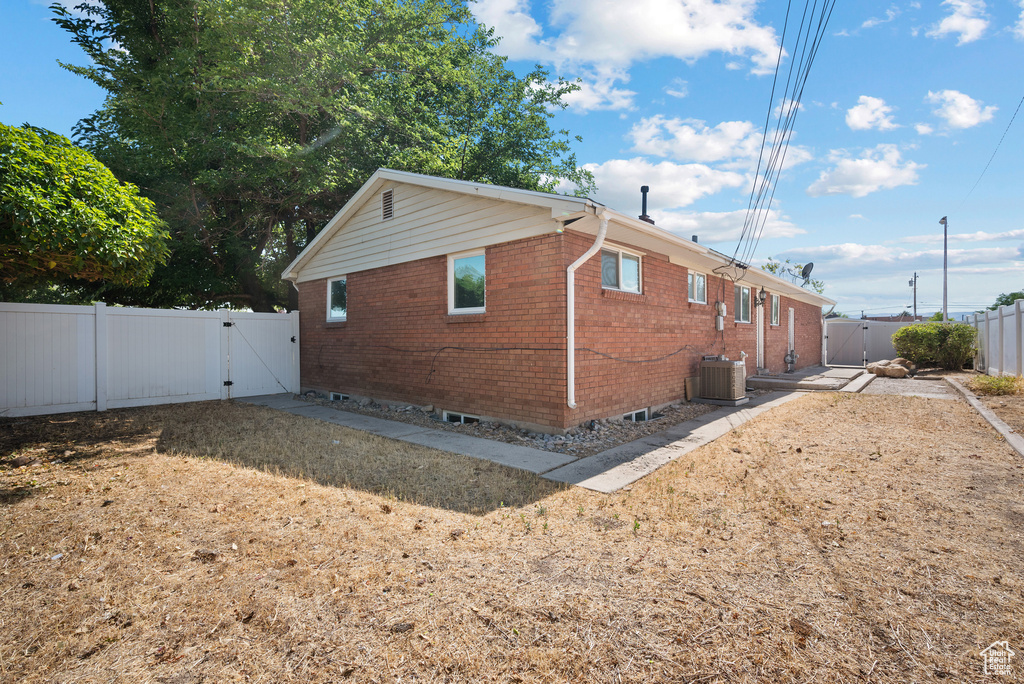 View of home's exterior with a gate, brick siding, and a fenced backyard