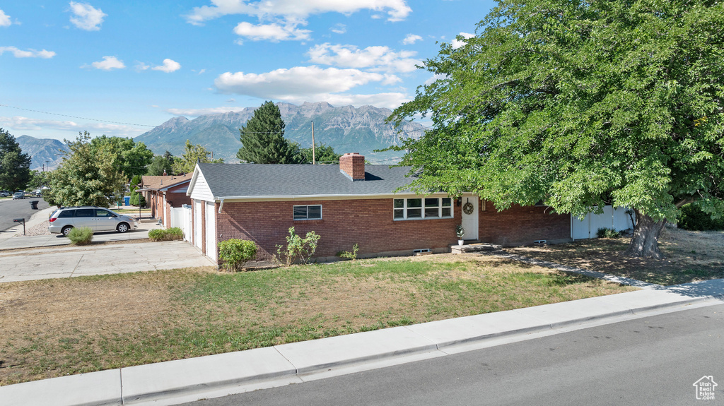 Single story home with brick siding, a mountain view, a chimney, and a garage