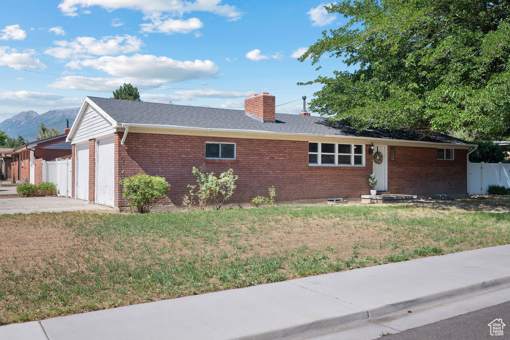 Ranch-style home featuring brick siding, an attached garage, a chimney, and a mountain view