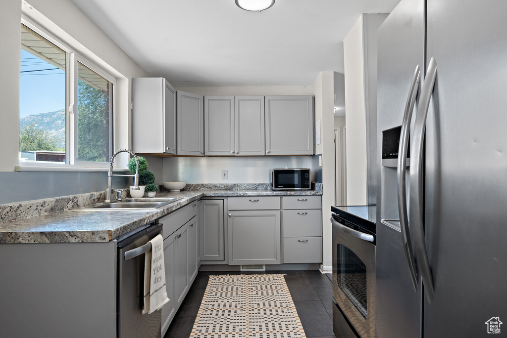 Kitchen featuring appliances with stainless steel finishes, light countertops, dark tile patterned floors, and gray cabinetry