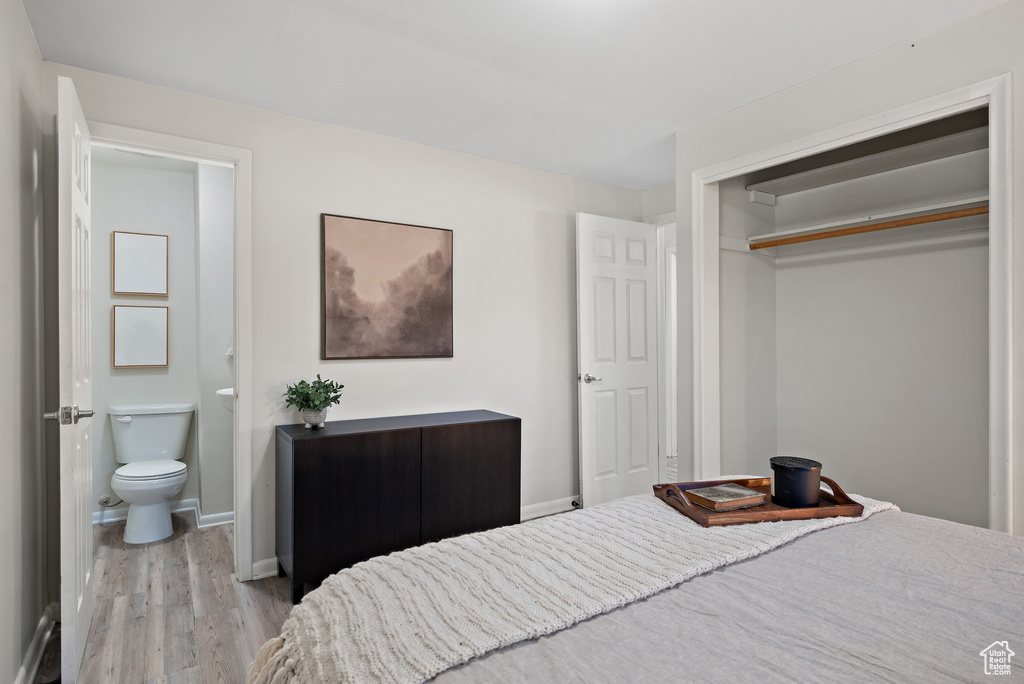 Bedroom featuring wood finished floors, a closet, and ensuite bath