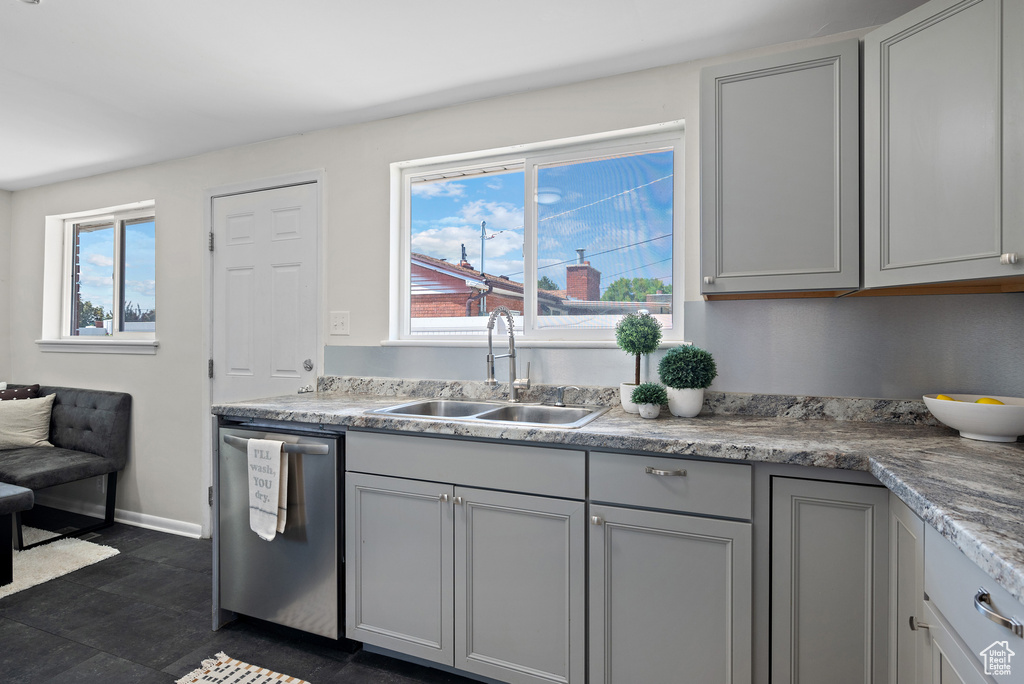 Kitchen with stainless steel dishwasher, light countertops, and gray cabinetry