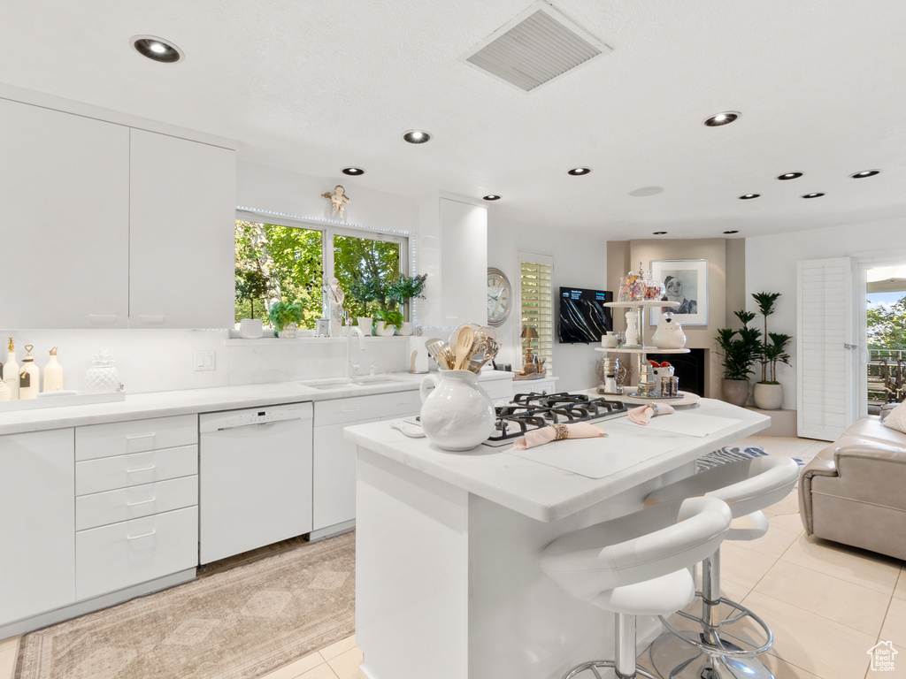 Kitchen featuring dishwasher, open floor plan, a center island, recessed lighting, and a breakfast bar