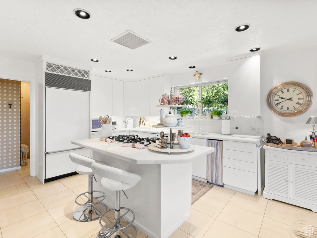 Kitchen featuring paneled fridge, gas stovetop, light countertops, white cabinetry, and recessed lighting