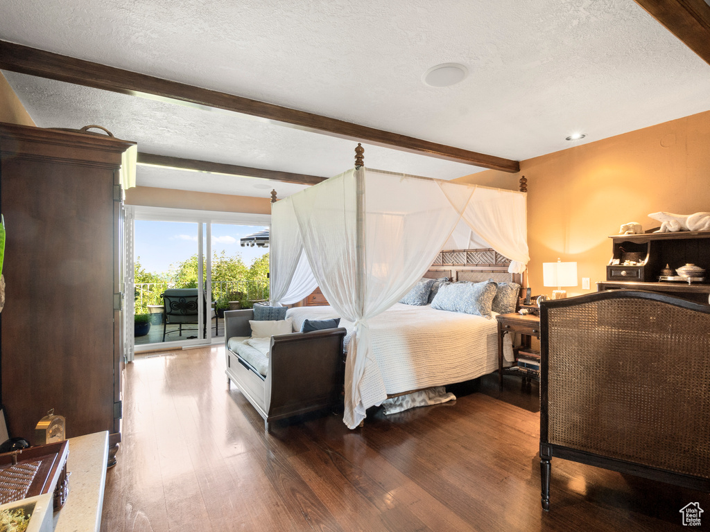 Bedroom featuring beam ceiling, wood finished floors, and a textured ceiling