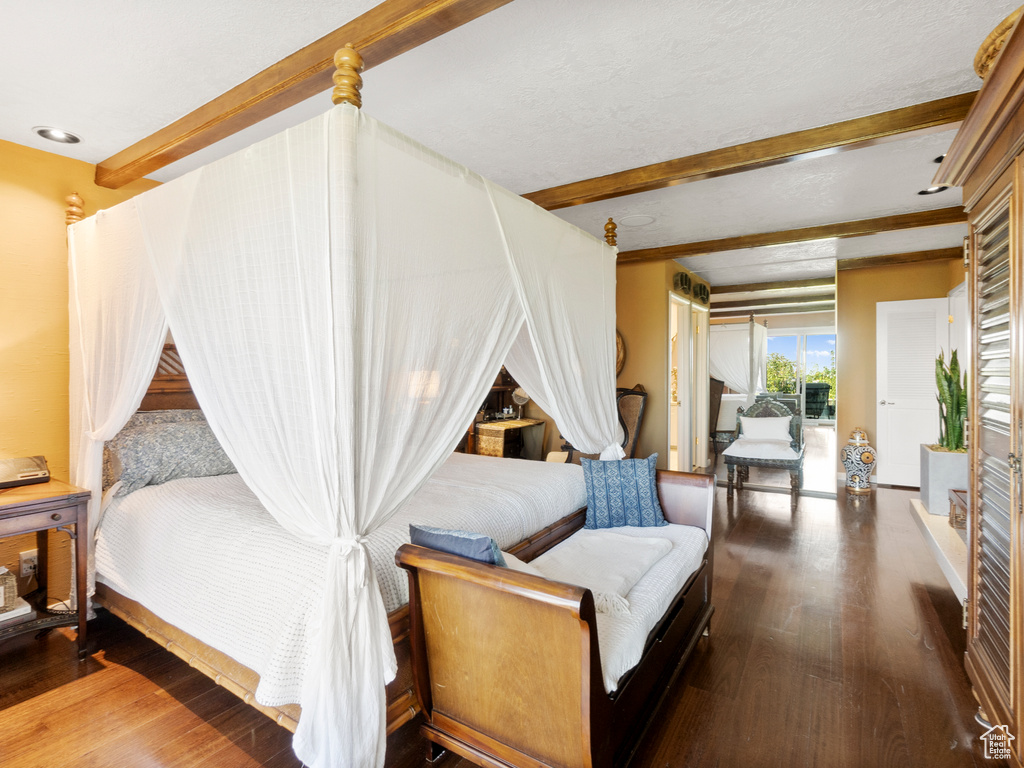 Bedroom with beamed ceiling and wood finished floors