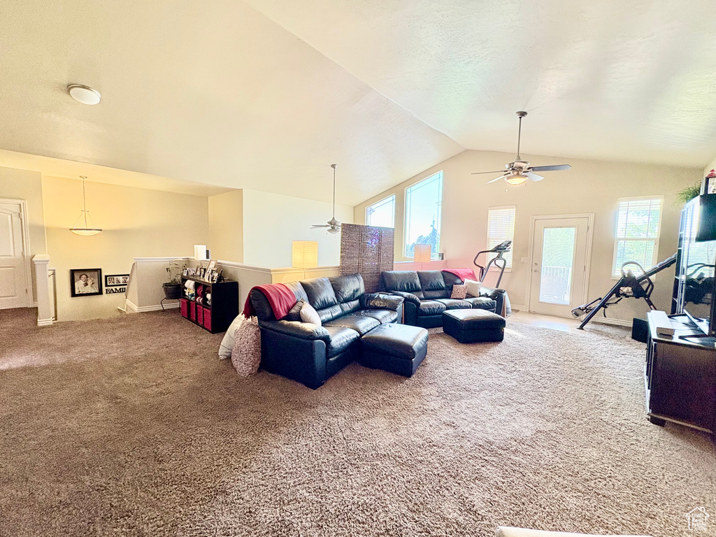 Carpeted living room featuring a ceiling fan, vaulted ceiling, and healthy amount of natural light