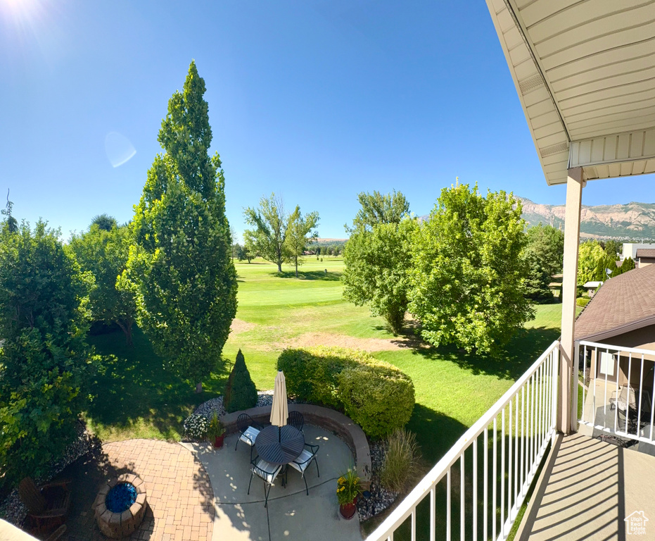 View of grassy yard featuring a mountain view, a patio, and a balcony