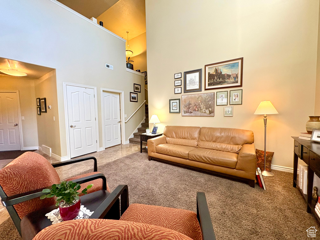 Carpeted living room with a towering ceiling and stairs