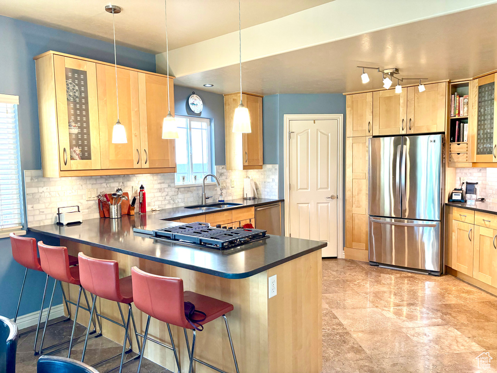 Kitchen featuring stainless steel appliances, dark countertops, backsplash, a peninsula, and glass insert cabinets